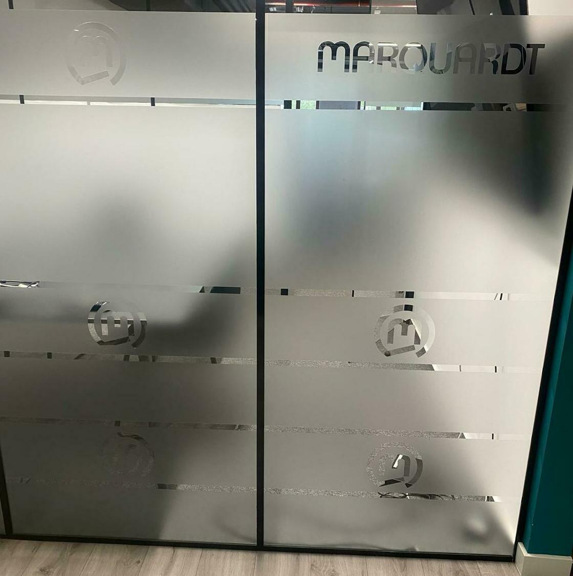 Folie sablată personalizată pentru birouri Marquardt Aplicare folie sablată personalizată în birourile companiei Marquardt, design elegant și profesional pentru ambient interior.